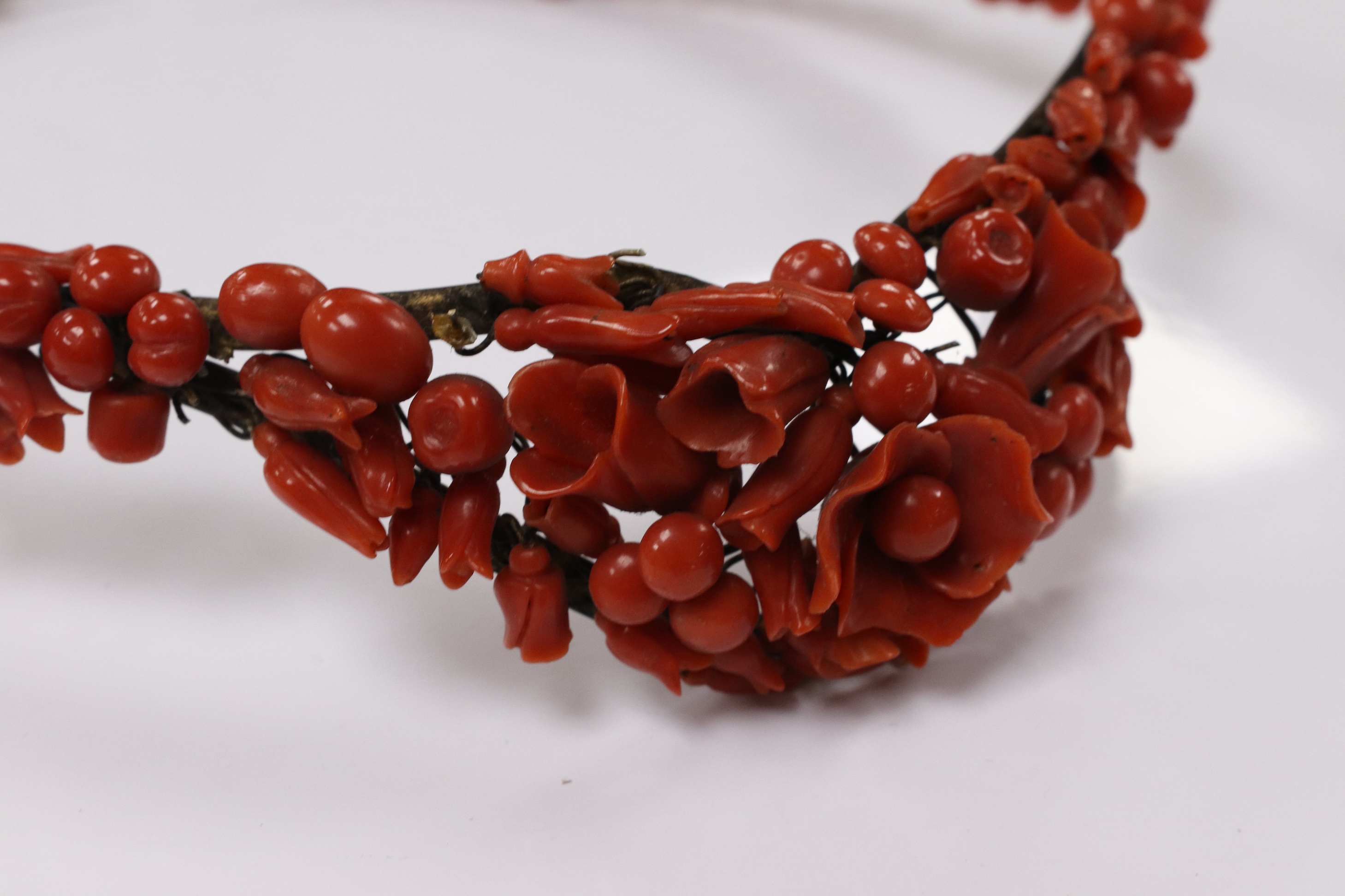 A 19th century base metal and coral bead floral designed tiara, approximately 40cm. Condition - poor to fair (some coral detached pieces in a small bag)